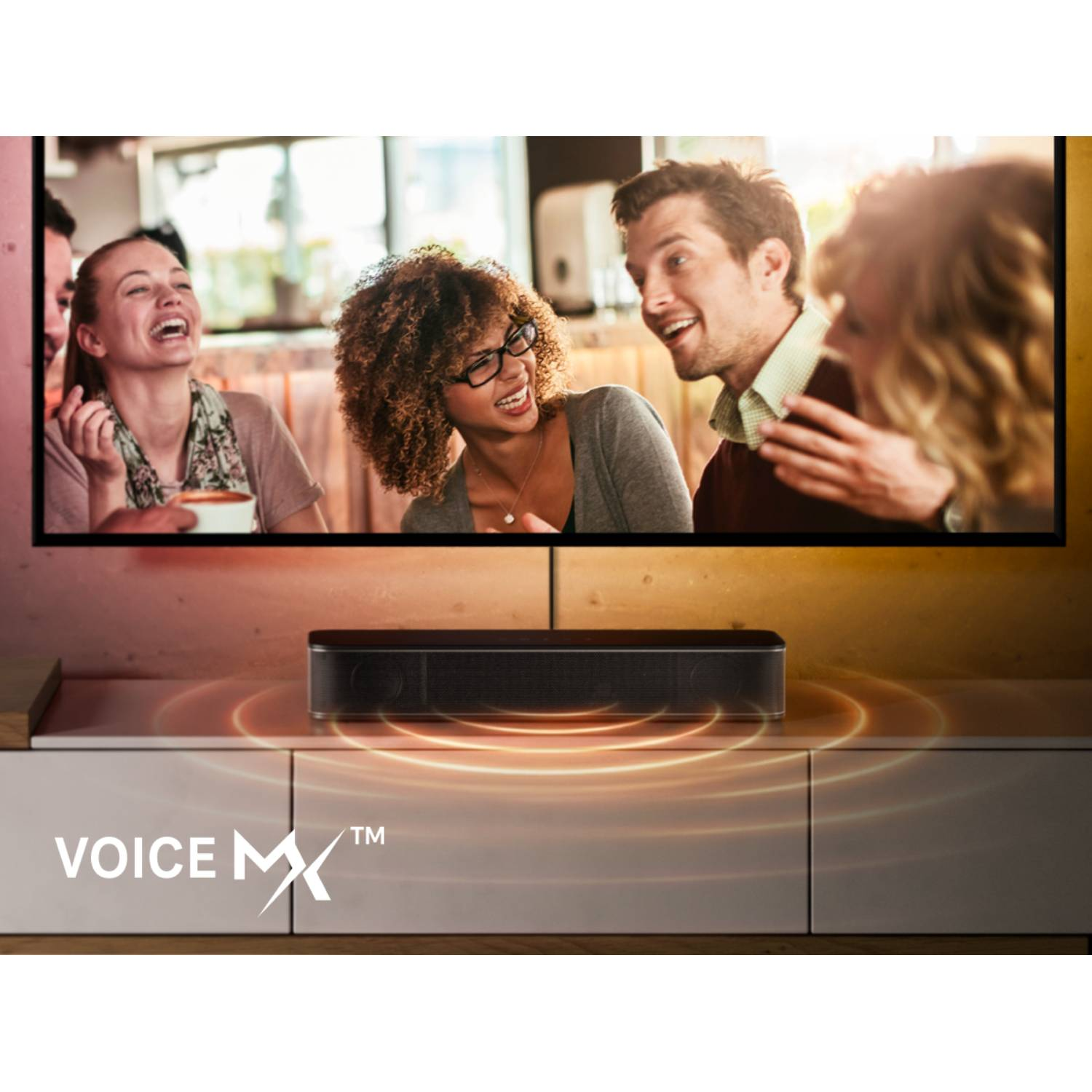 Przyjaciele śmieją się przed telewizorem; soundbar przed nim.