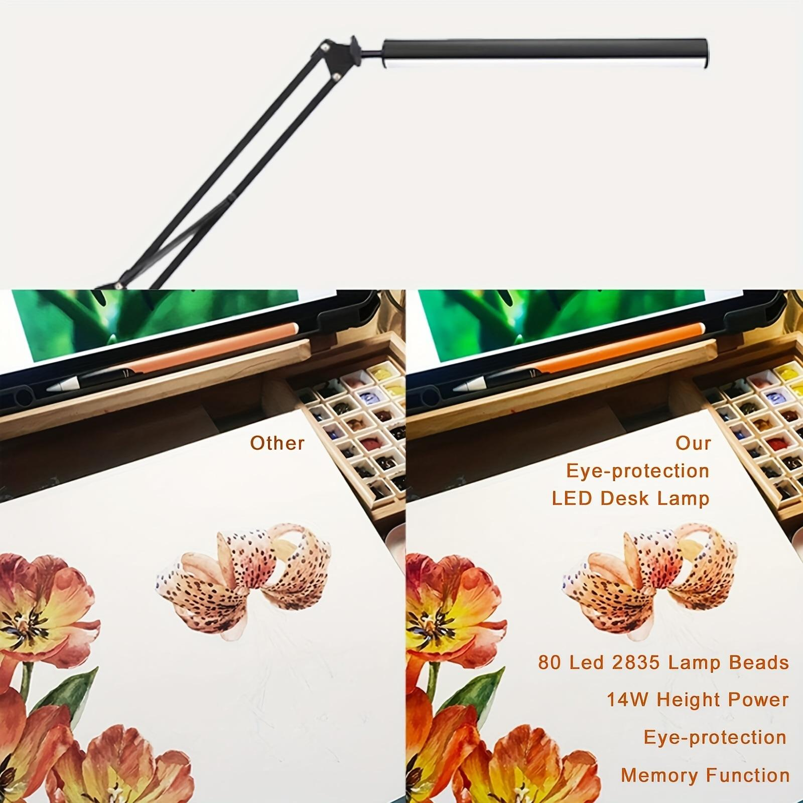 Ein Schreibtisch mit einer Lampe, Aquarellfarben und Blumenmalereien.