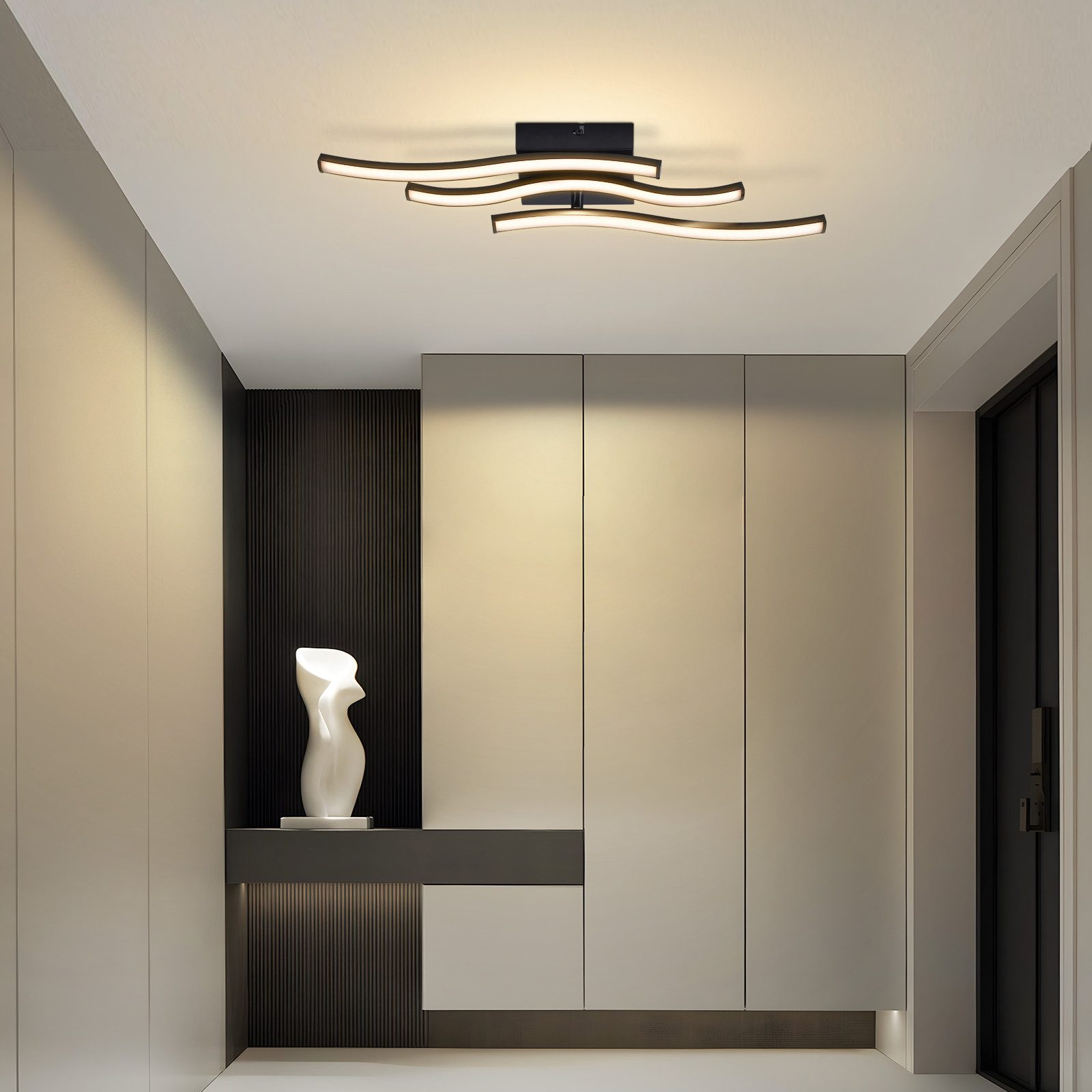 Lampadario moderno sopra scultura bianca e parete di armadi.