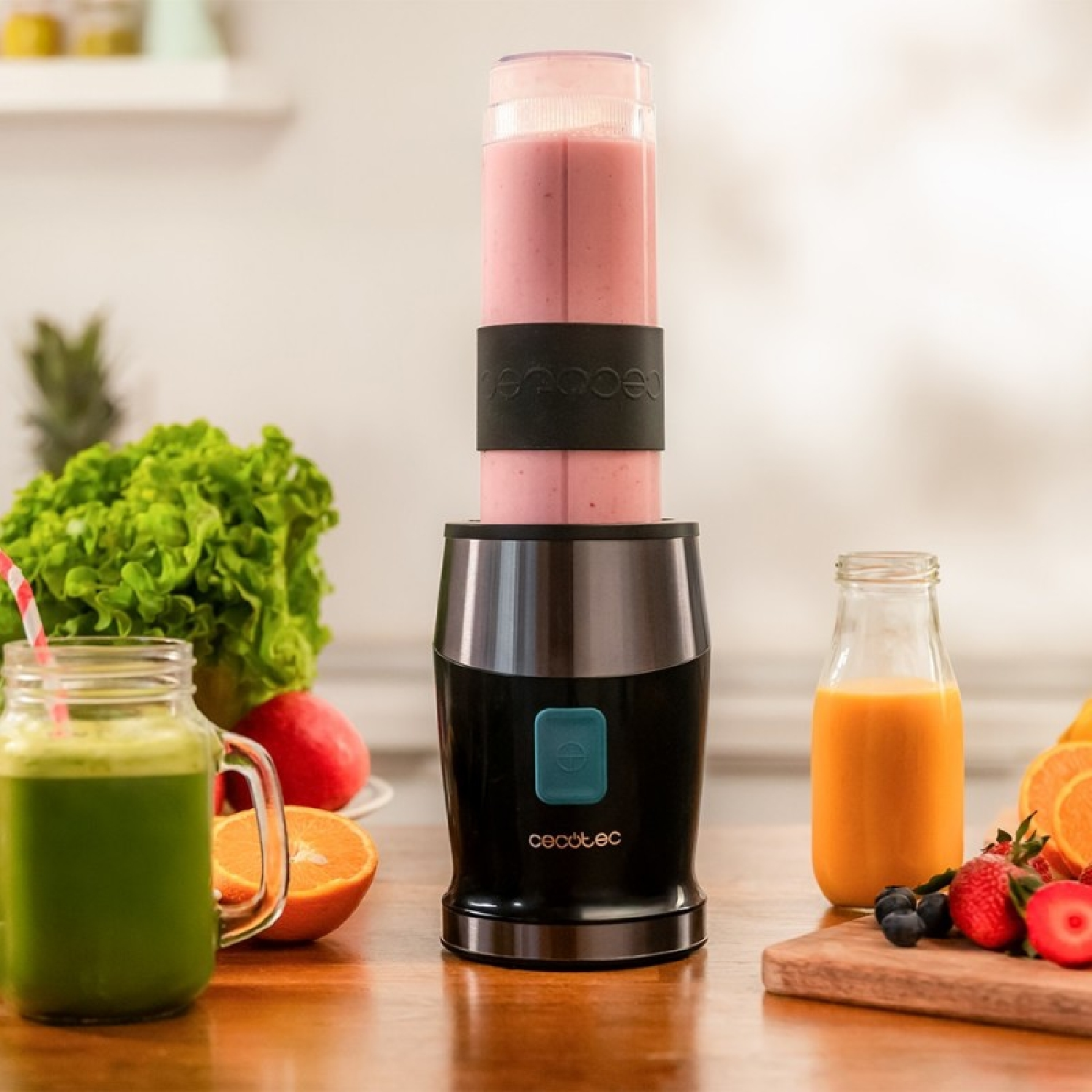 Ein Mixer mit einem rosa Smoothie, daneben grüne und orangefarbene Säfte, Früchte.