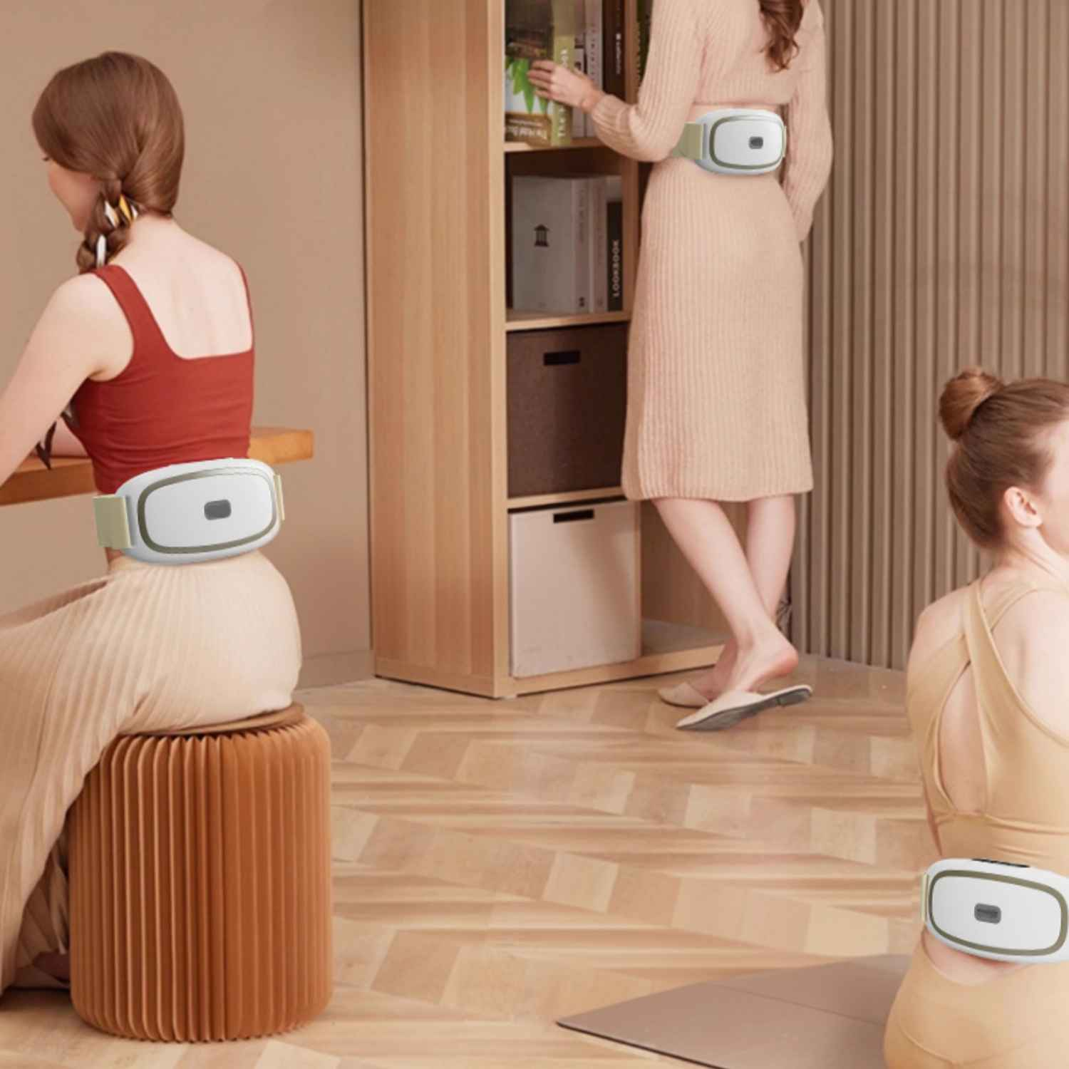 Drei Frauen mit Massagegeräten um die Taille, eine sitzt auf einem Hocker.