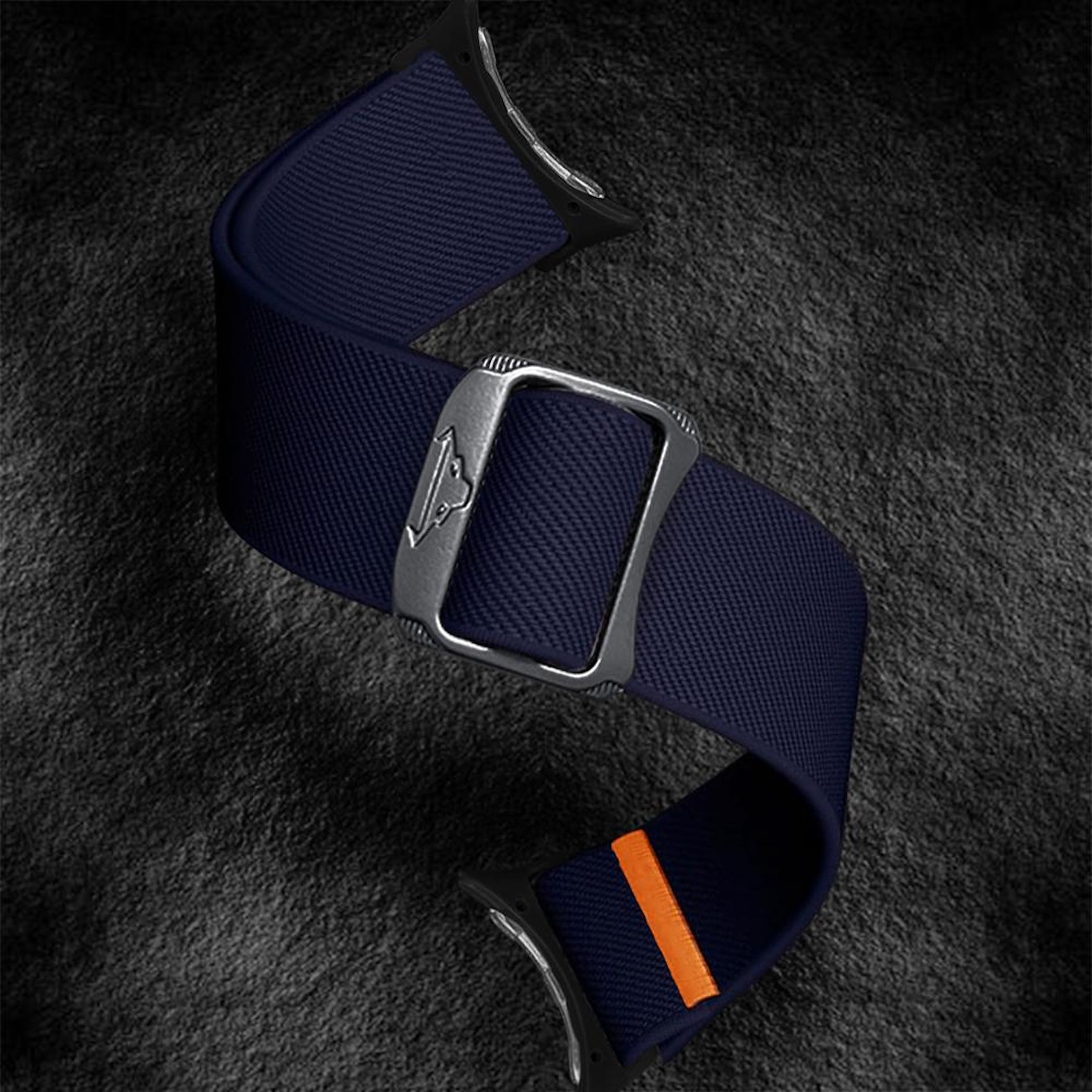 Ein dunkelblaues Uhrenarmband mit silberner Schnalle liegt auf dunklem Grund.
