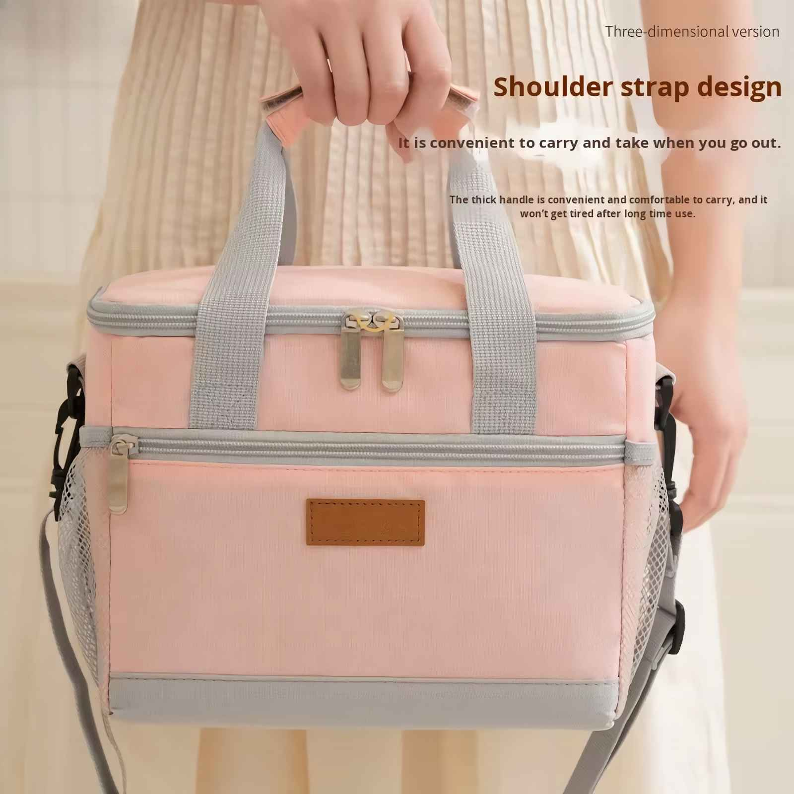 Eine Person hält eine rosafarbene Kühltasche mit zwei Fächern und grauen Griffen.
