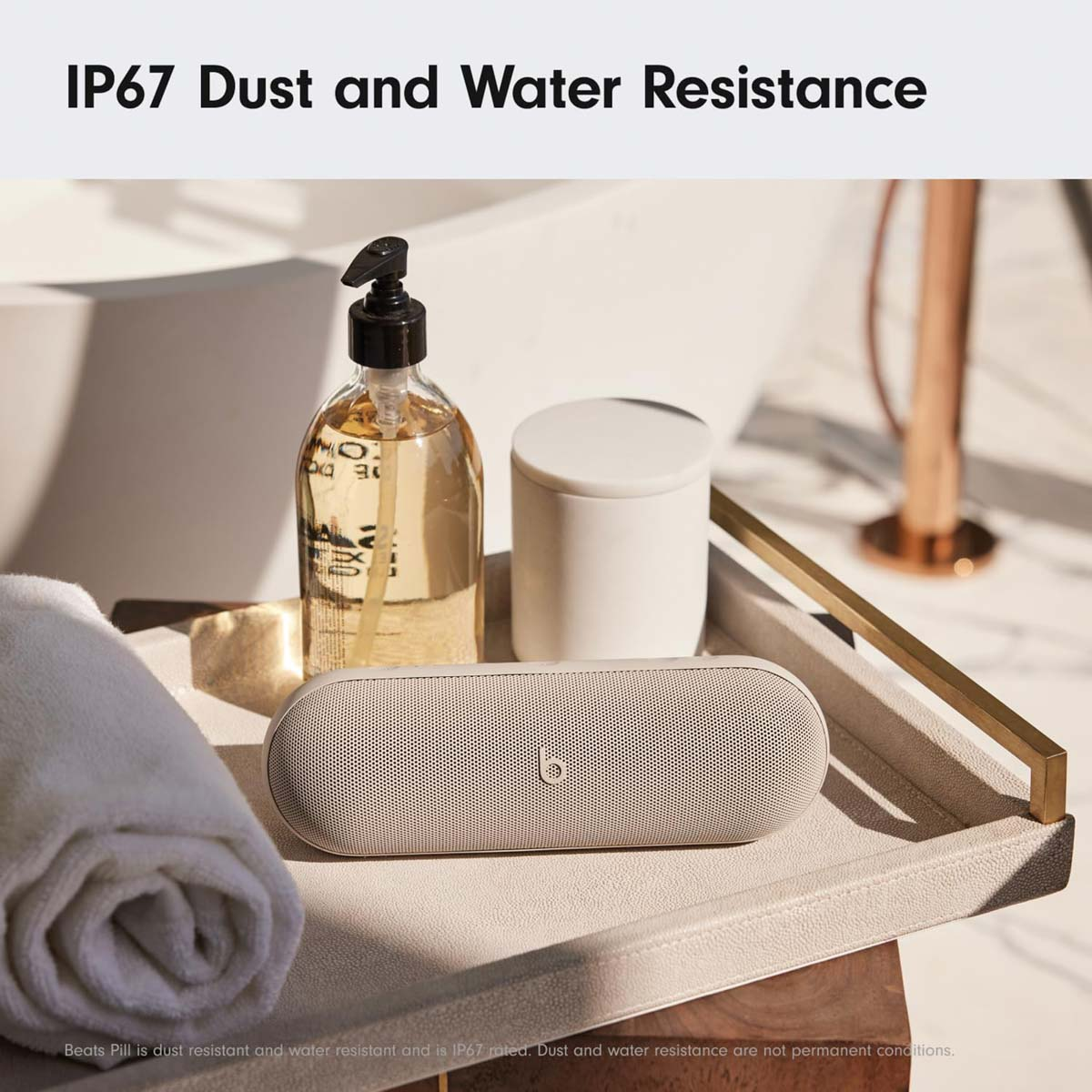Een beige Beats Pill speaker op een dienblad met zeep en handdoek.