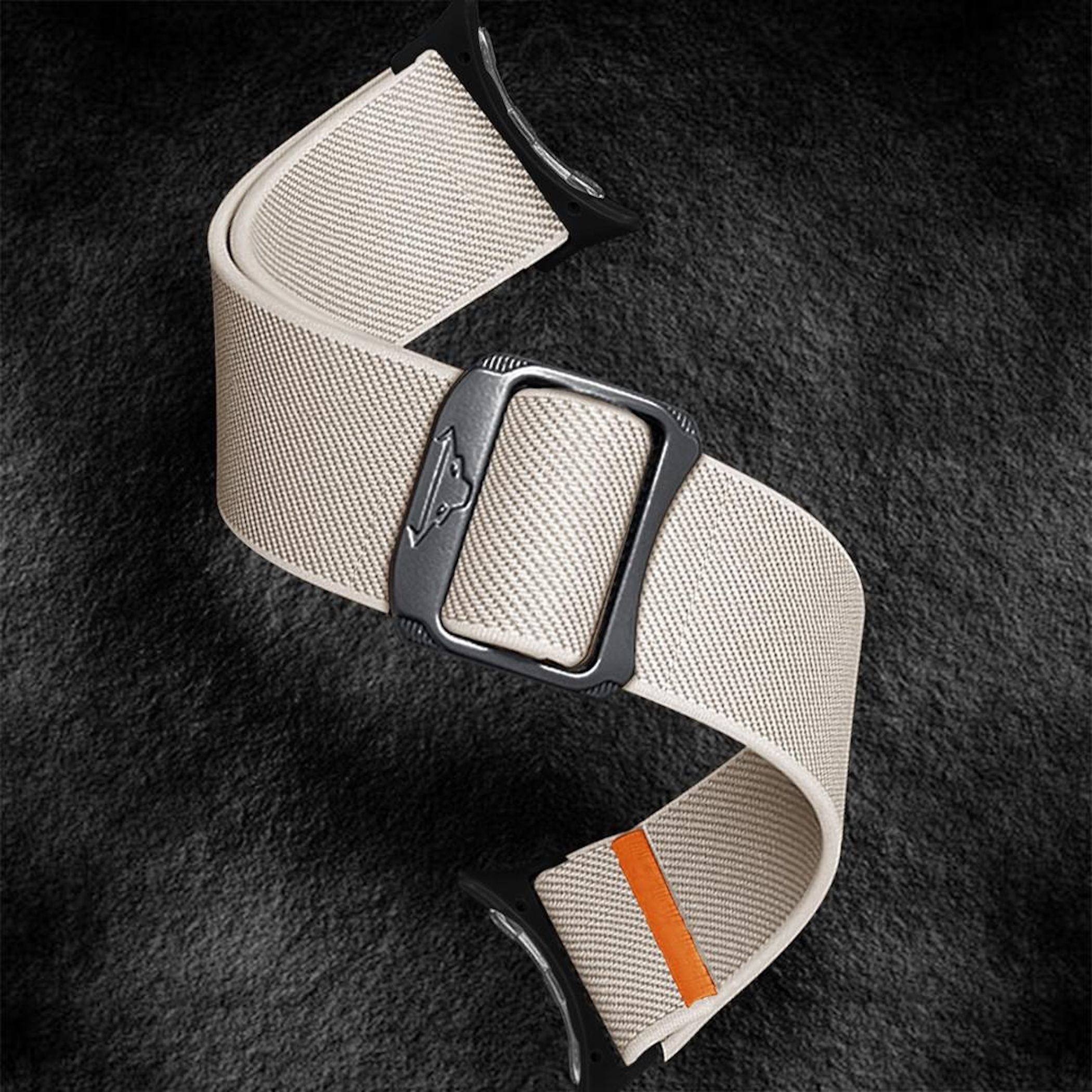 Ein hellbraunes Stoffarmband mit Metallschnalle und orangefarbenem Akzent.