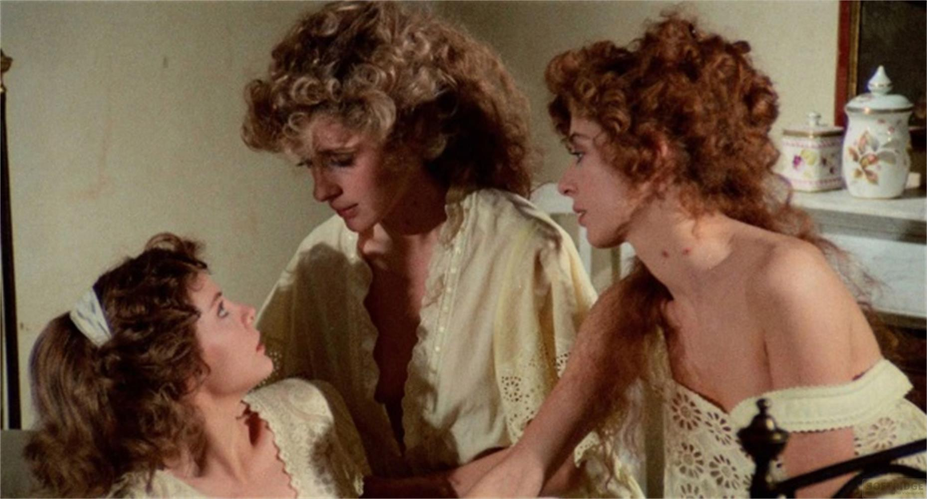 Tre donne con capelli ricci in abiti pallidi su un letto.