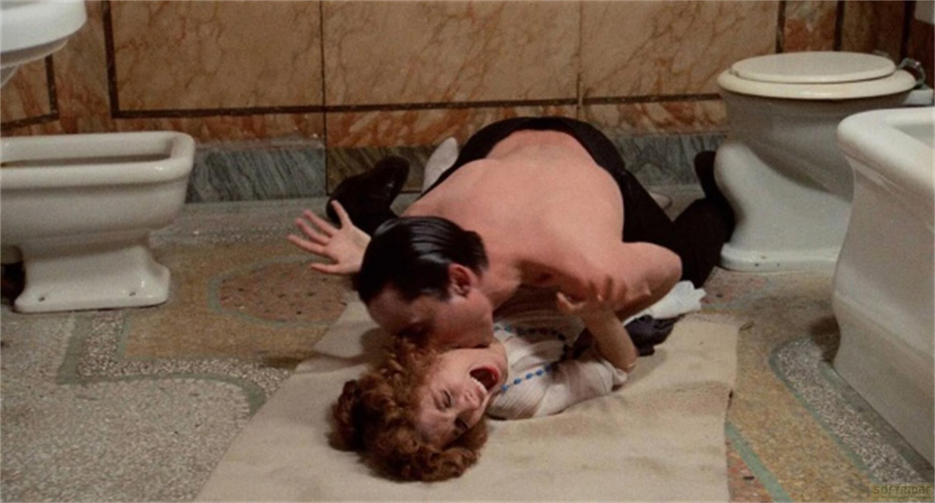 Un uomo e una donna giacciono sul pavimento di un bagno accanto ai water.