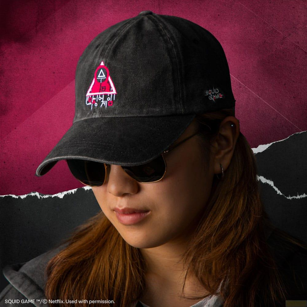Una mujer con gafas de sol y gorra negra con el logo de Squid Game.
