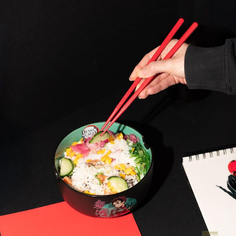 Una mano usa palillos rojos para recoger pepino de un poke bowl con arroz, atún, maíz y verduras.