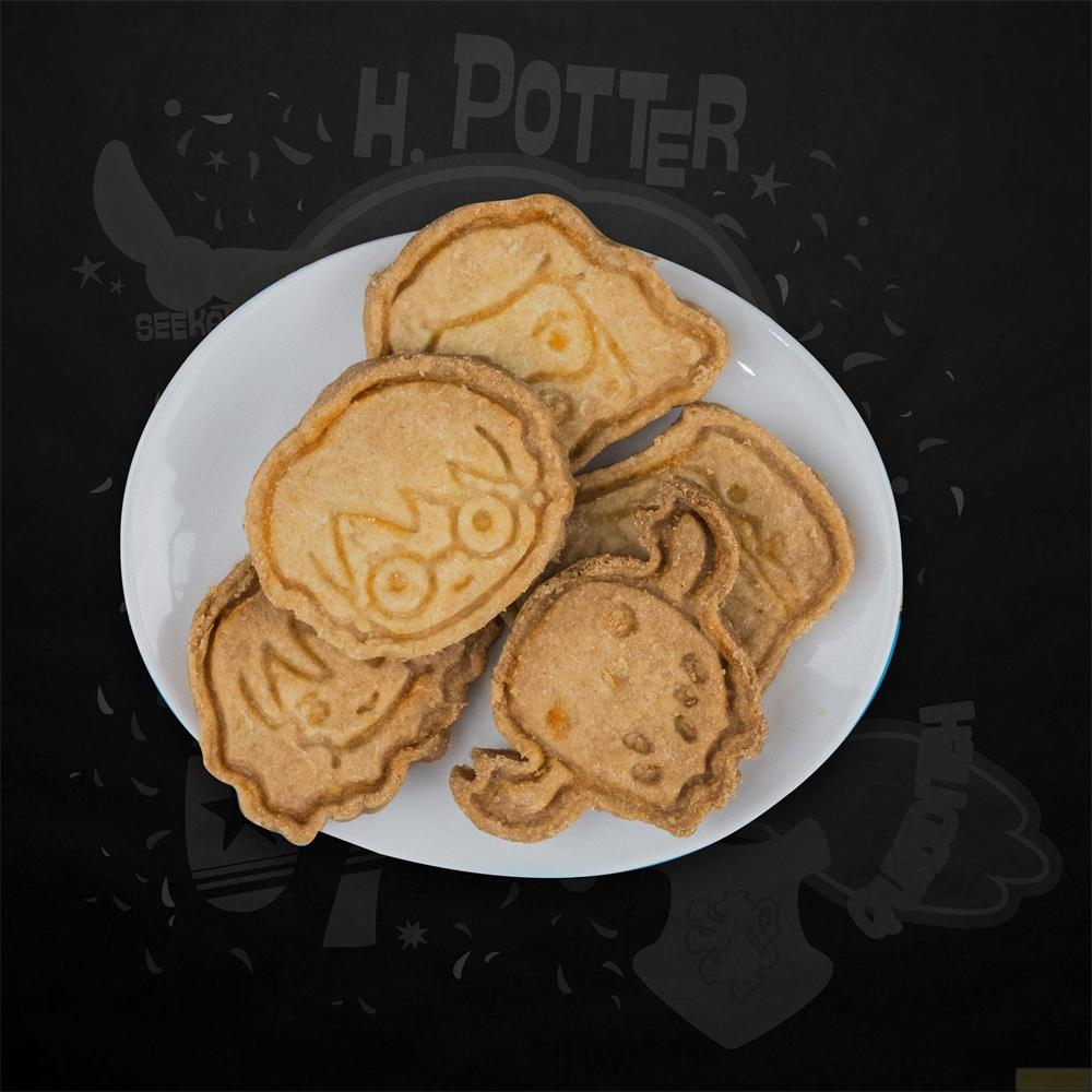 Ein weißer Teller mit fünf Harry Potter Keksen. Die Kekse sind geformt wie Charaktere und Symbole.