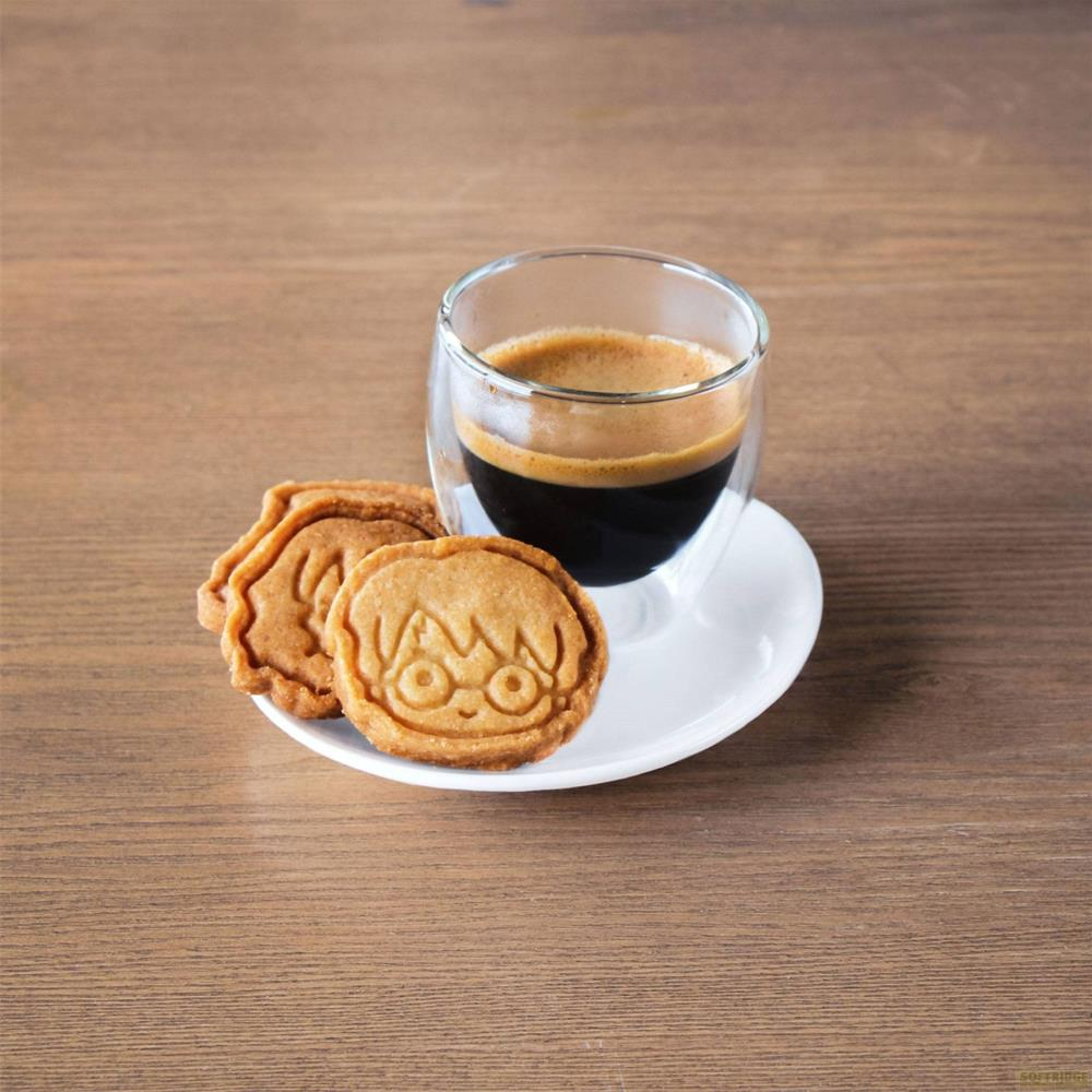 Eine Tasse Espresso mit zwei Keksen auf einer Untertasse auf einem Holztisch.