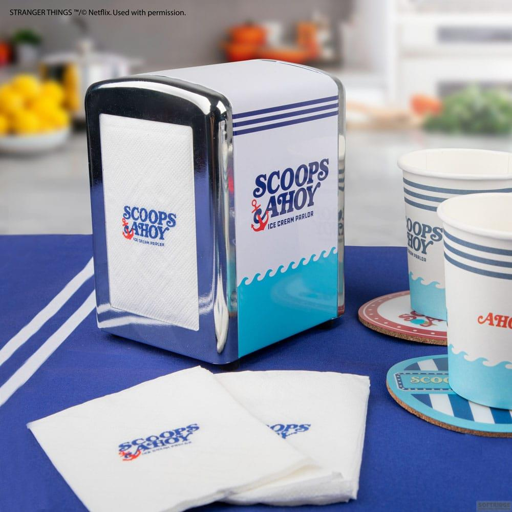 Un dispensador de servilletas plateado con el logo de Scoops Ahoy, servilletas y vasos al lado.