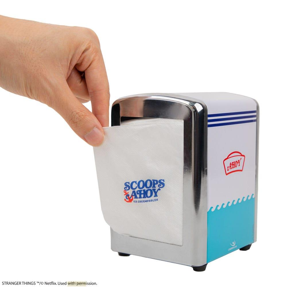 Una mano saca una servilleta de un dispensador blanco con el logo "Scoops Ahoy".