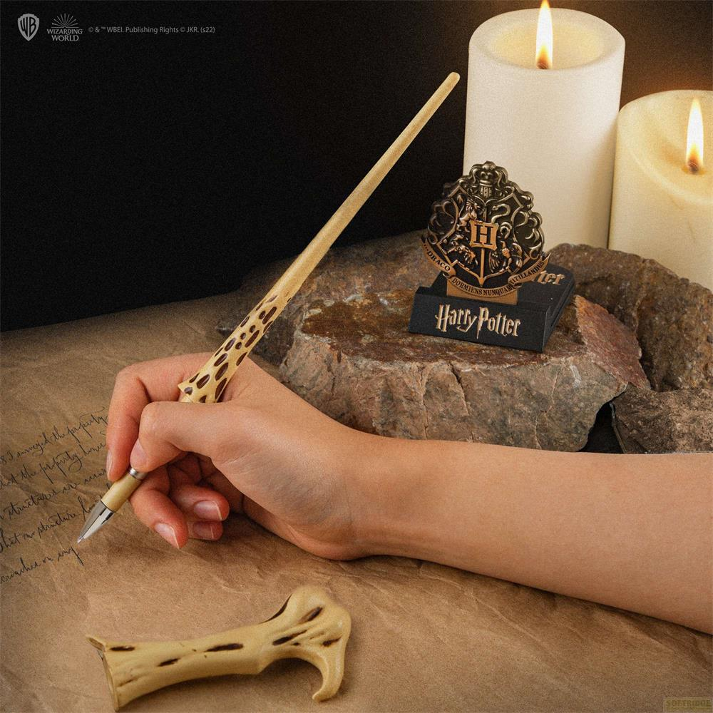 Una mano tiene una bacchetta di Harry Potter, scrive su pergamena vicino a candele.