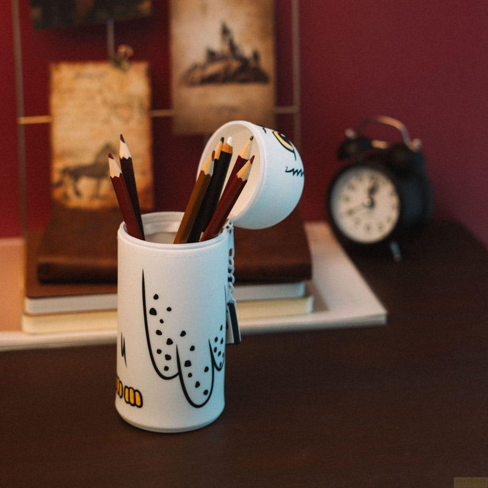 Portalápices blanco de búho con lápices de colores, junto a libros y despertador.