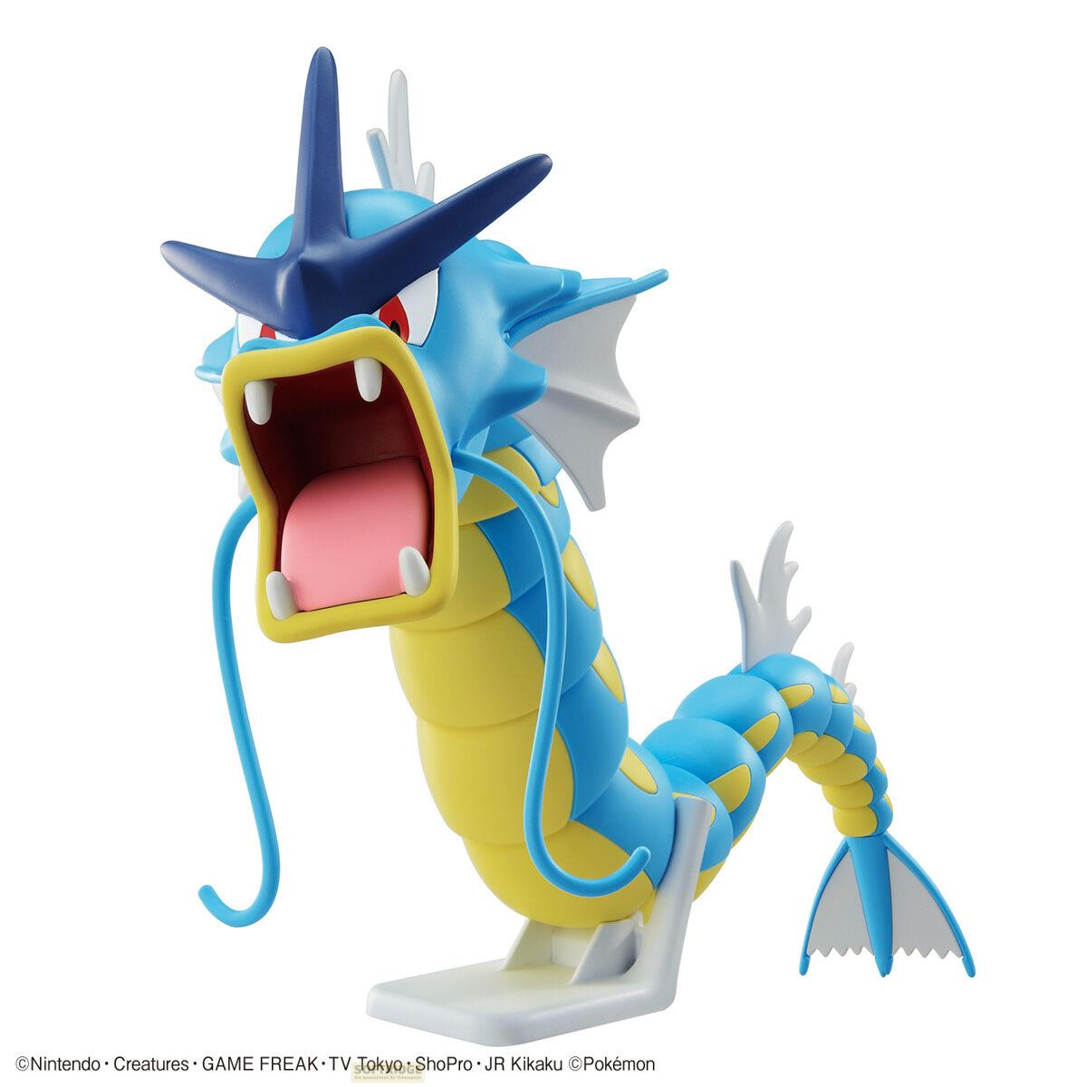 Une figurine de dragon bleu et jaune, bouche ouverte, sur un support blanc.