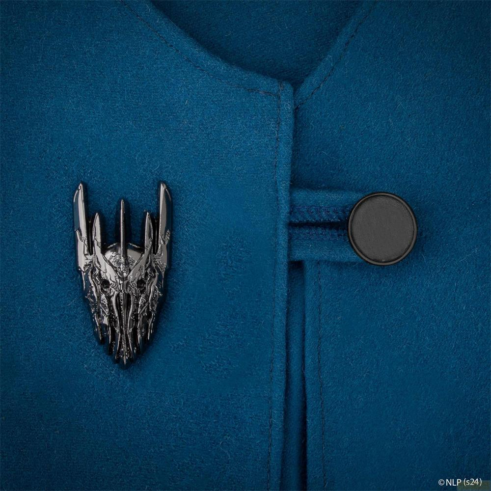 Un pin plateado con forma de calavera sobre tela azul con botón.