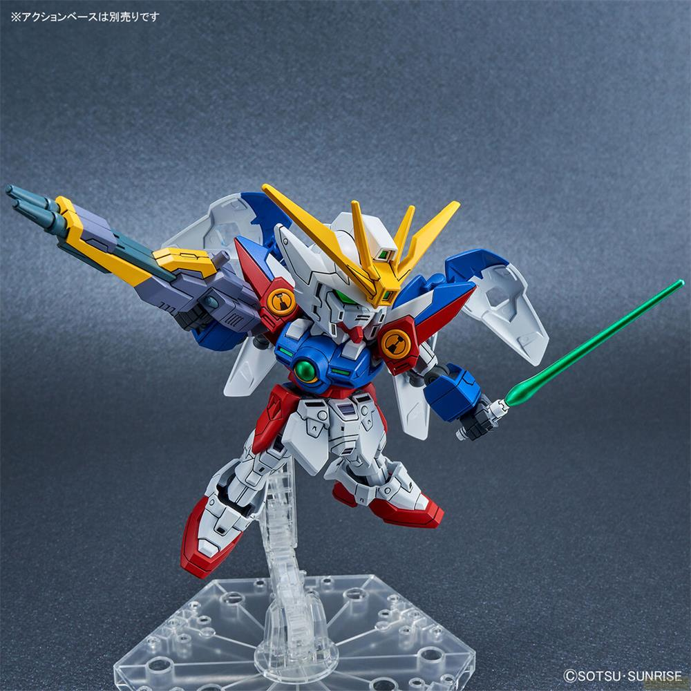 Un robot Gundam coloré avec sabre laser vert et canon, posé sur un support.