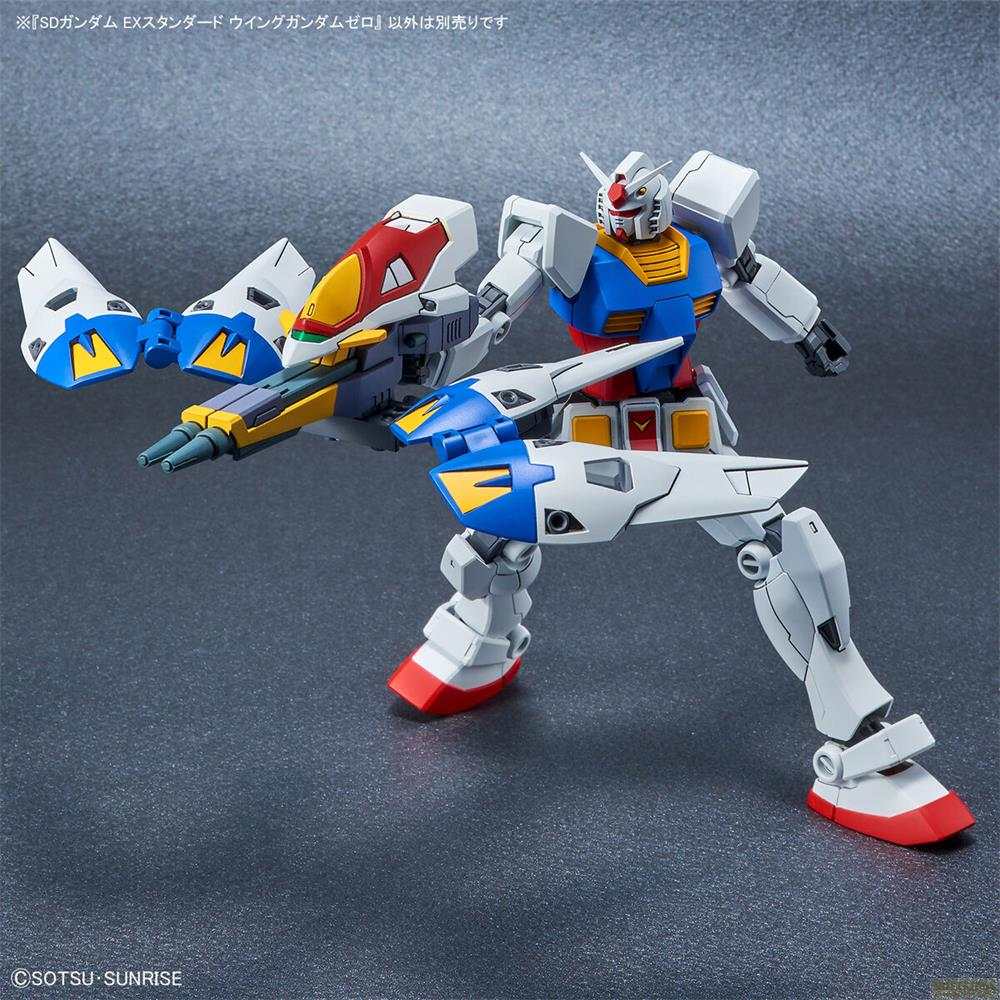Un robot Gundam blanc aux accents bleus, rouges et jaunes tient une arme.