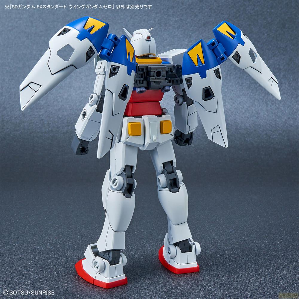 Un robot Gundam blanc aux accents bleus et jaunes se tient sur fond sombre.