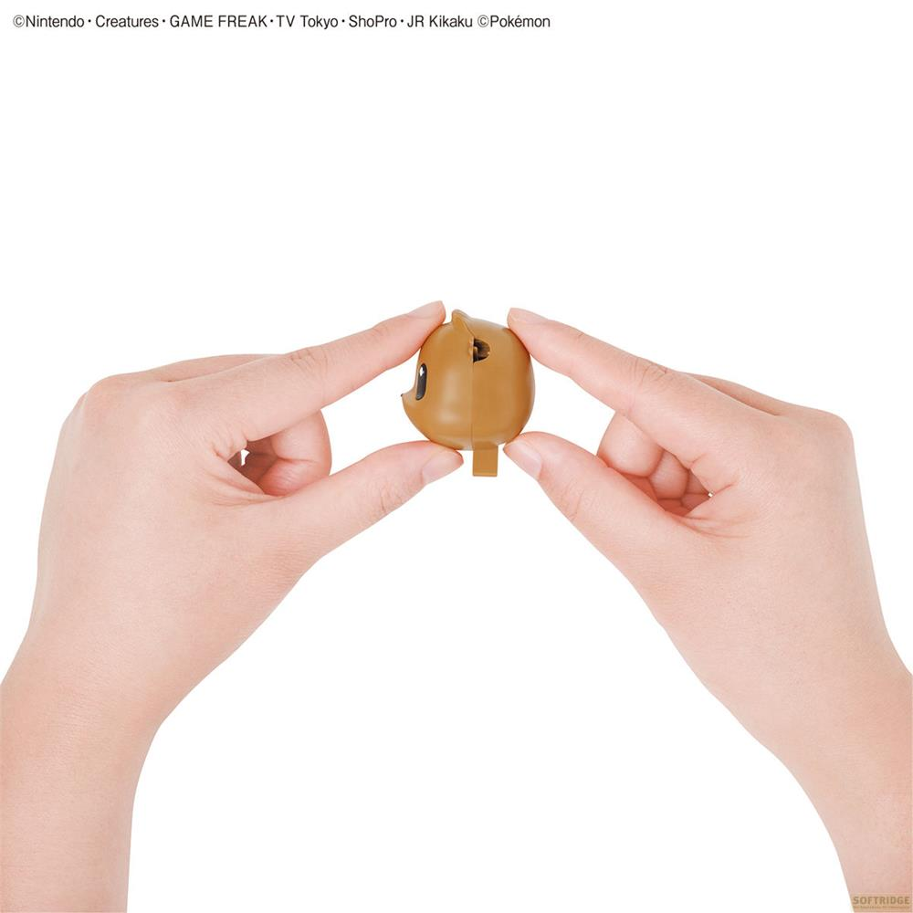 Figurine marron tenue par deux mains, sur fond blanc.
