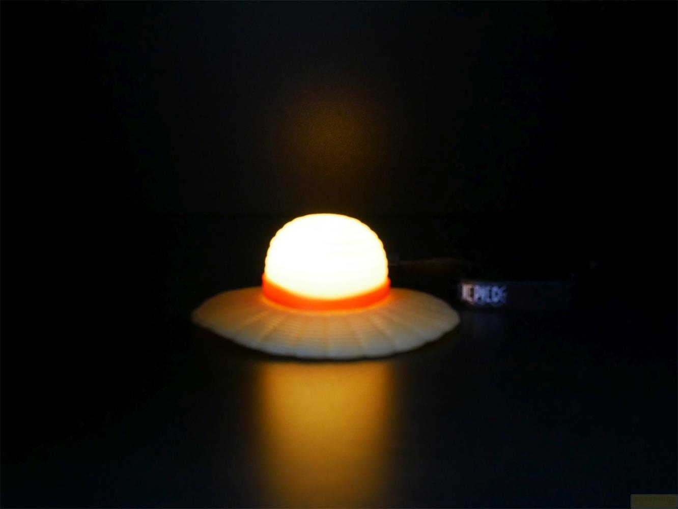 Une lumière blanche en dôme lumineux avec bande orange sur surface texturée.