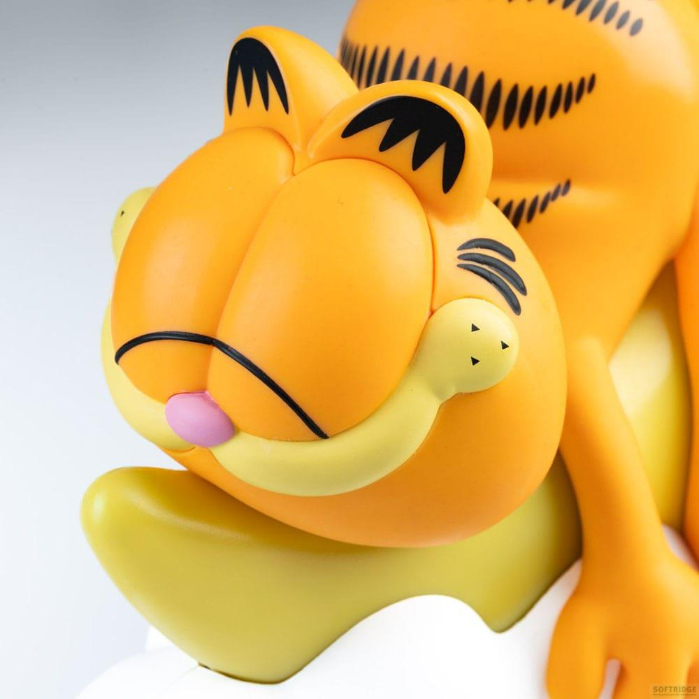 Una figura naranja de Garfield con ojos cerrados y nariz rosa descansa sobre una base amarilla.