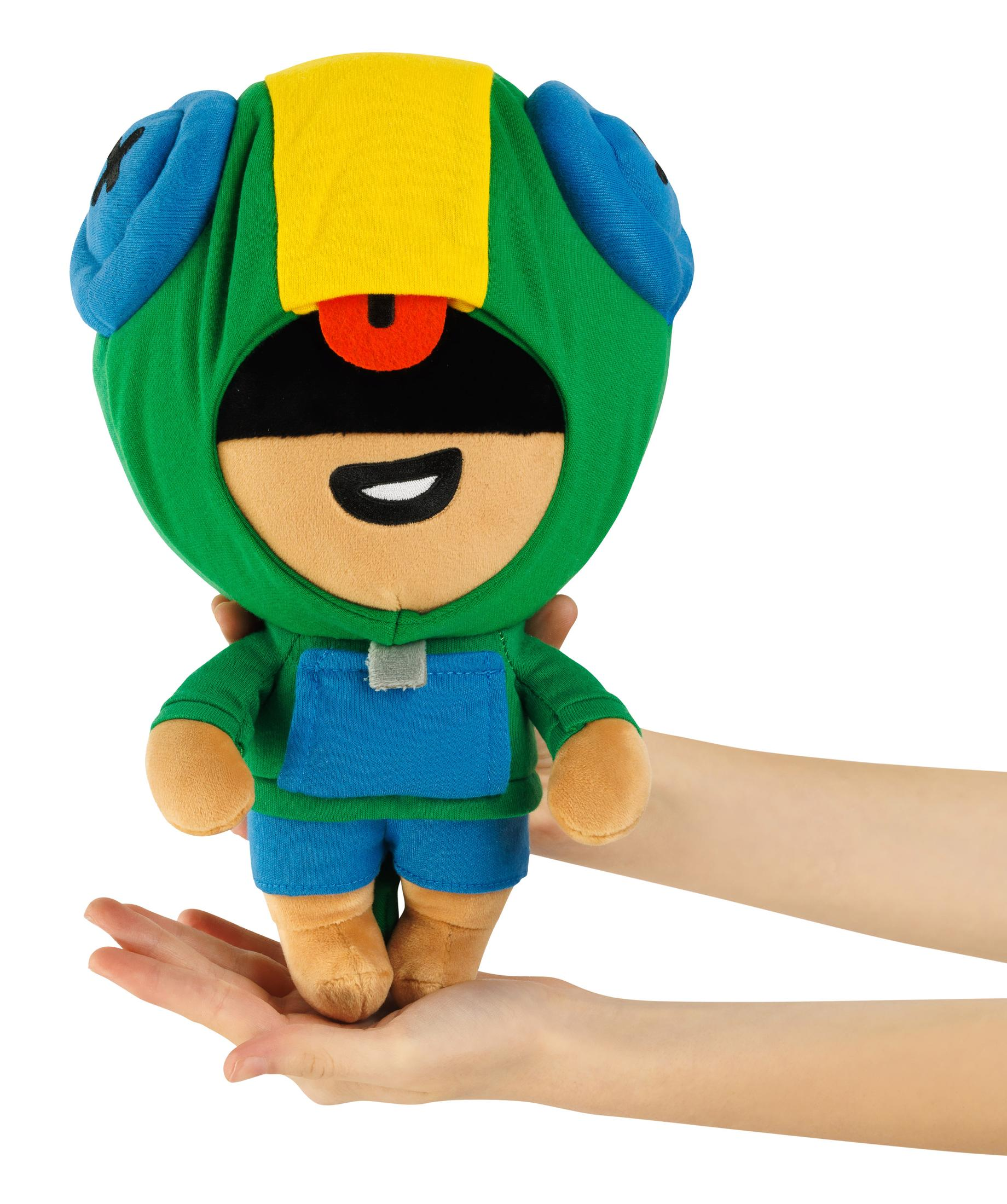 Un peluche con felpa verde, tuta blu e maschera gialla, tenuto dalle mani.