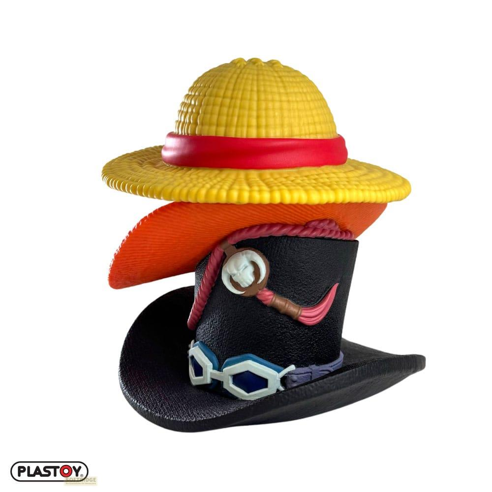 Tres sombreros apilados: sombrero de paja, sombrero naranja y chistera negra con gafas.