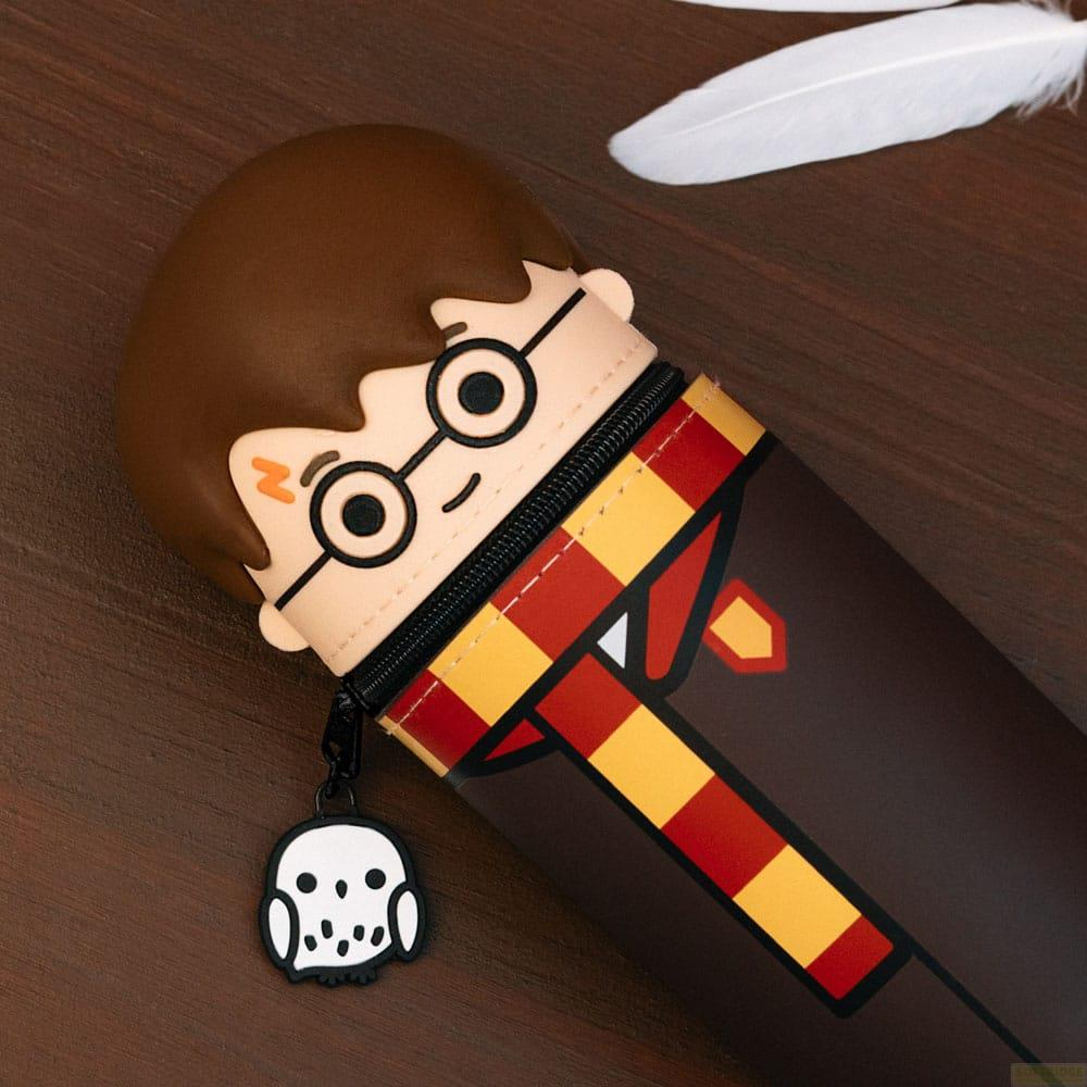 Un estuche de Harry Potter con amuleto de Hedwig sobre madera.