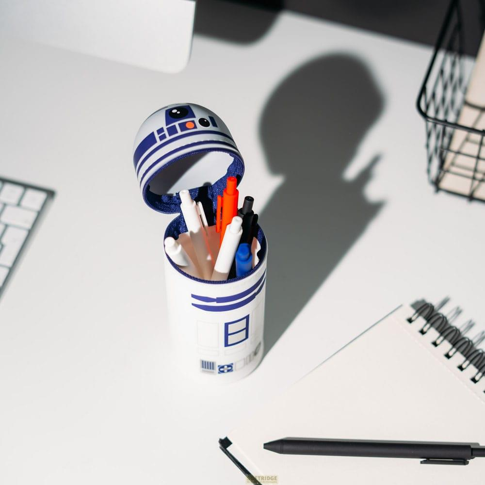 Un portalápices R2-D2 con bolígrafos sobre un escritorio.