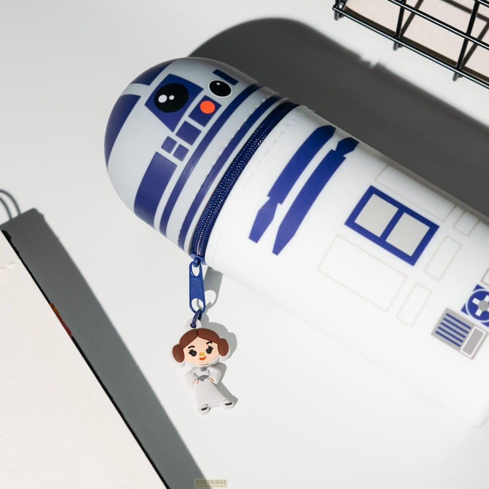 Estuche R2-D2 con charm de Leia sobre superficie blanca.