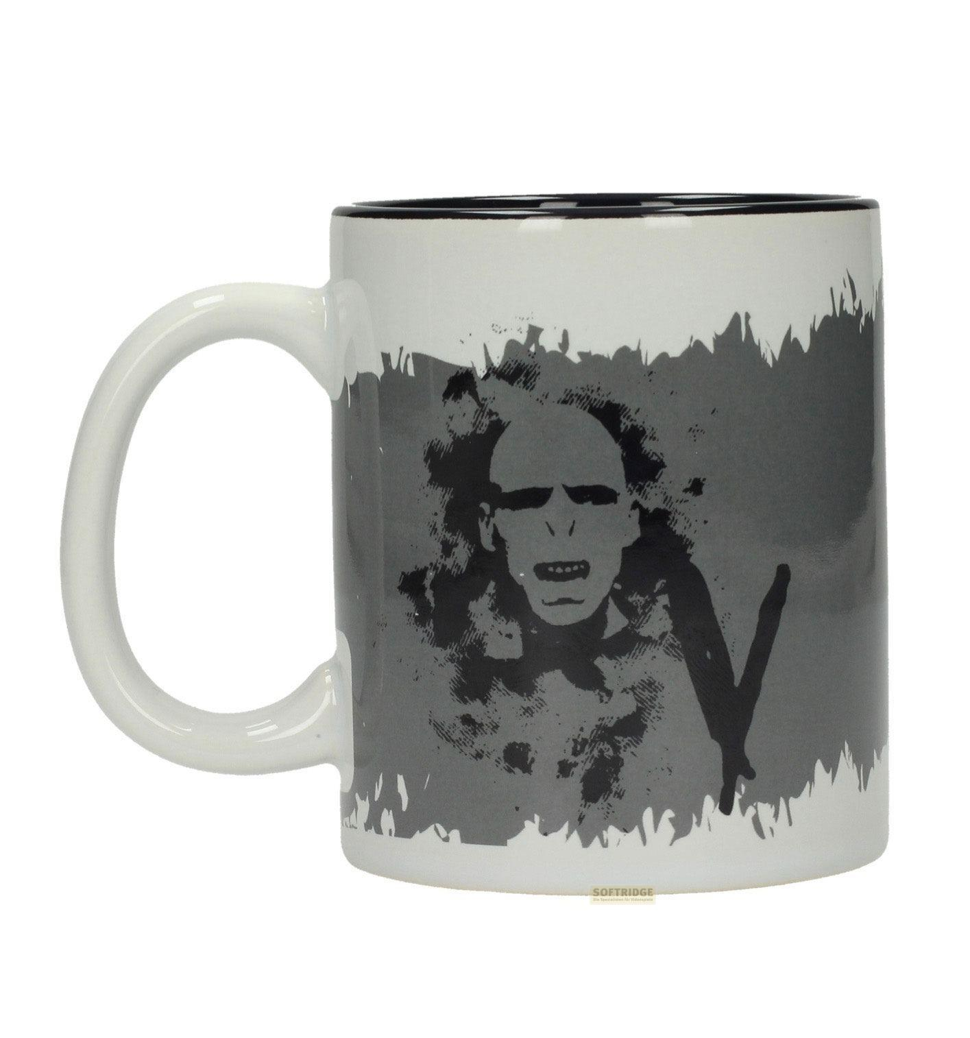 Una taza blanca con estampado de rostro amenazante en escala de grises.