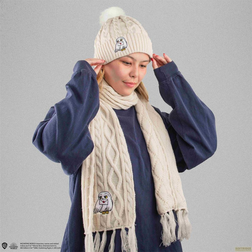 Eine Frau mit einem gestrickten beige Mütze und Schal mit Eulenaufdruck.