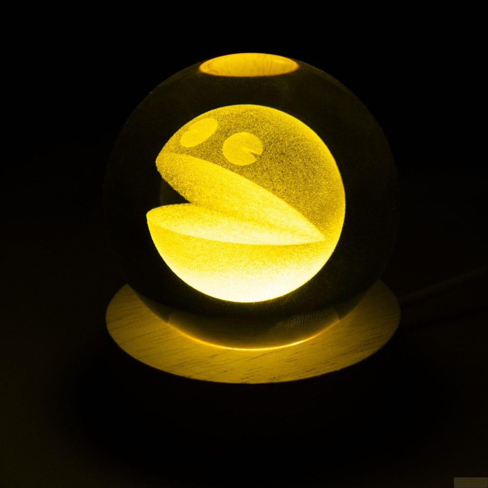 Esfera amarilla de Pac-Man con base de madera sobre fondo negro.
