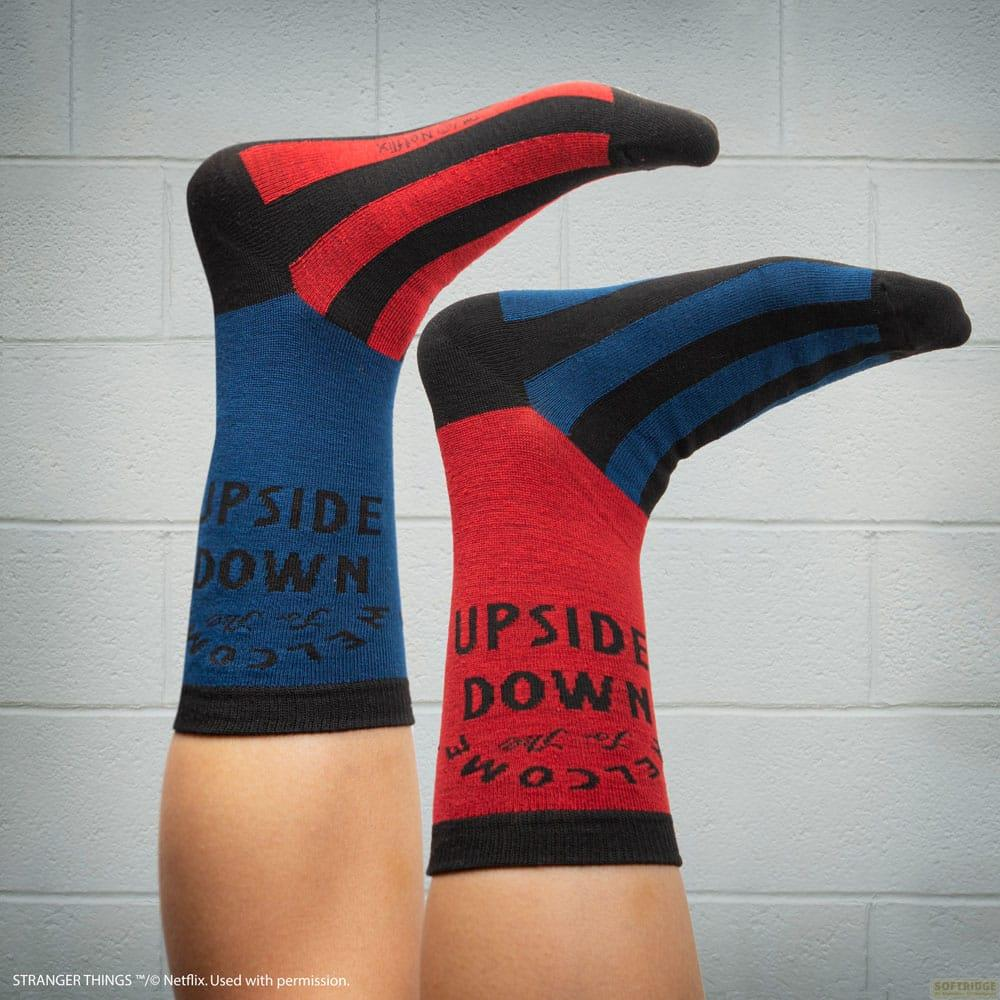 Dos piernas con calcetines a rayas, uno rojo, uno azul, con texto "UPSIDE DOWN".