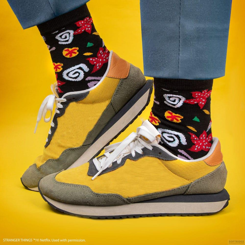 Zapatillas amarillas con ribete de ante gris y calcetines negros con hojas rojas.