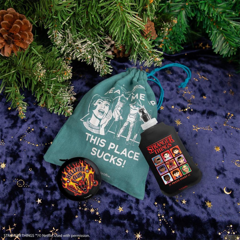 Artículos de Stranger Things: bolsa, pin y botella sobre terciopelo azul.