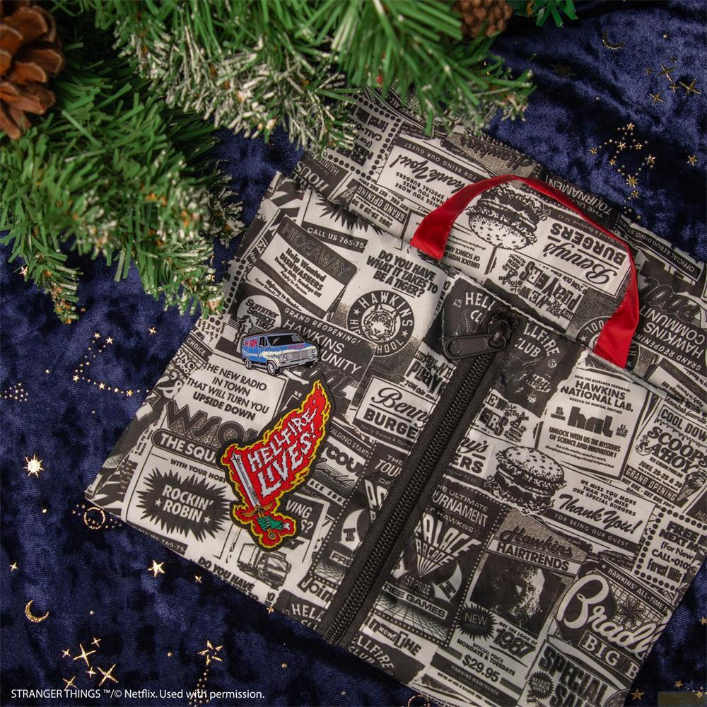 Una bolsa de Stranger Things con estampado de periódico, pines y vegetación navideña.