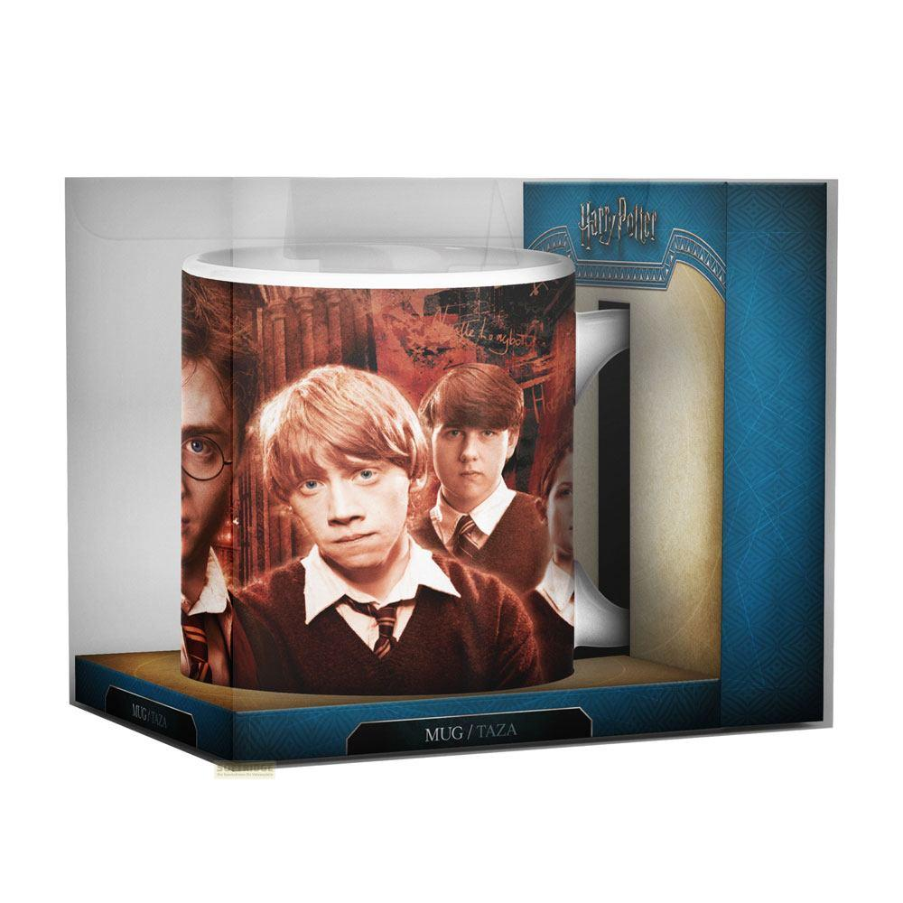 Una taza blanca con los personajes de Harry Potter, Ron, Harry y Hermione, en una caja transparente con base azul.
