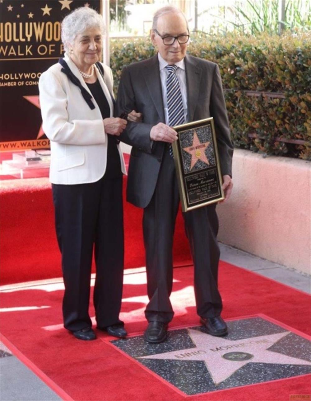 Una coppia anziana sul Hollywood Walk of Fame. La donna indossa una giacca bianca, l'uomo tiene una targa a stella.