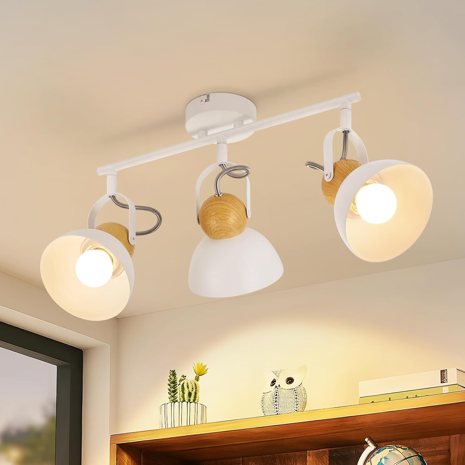 Biała lampa sufitowa z trzema regulowanymi reflektorami i drewnianymi akcentami.