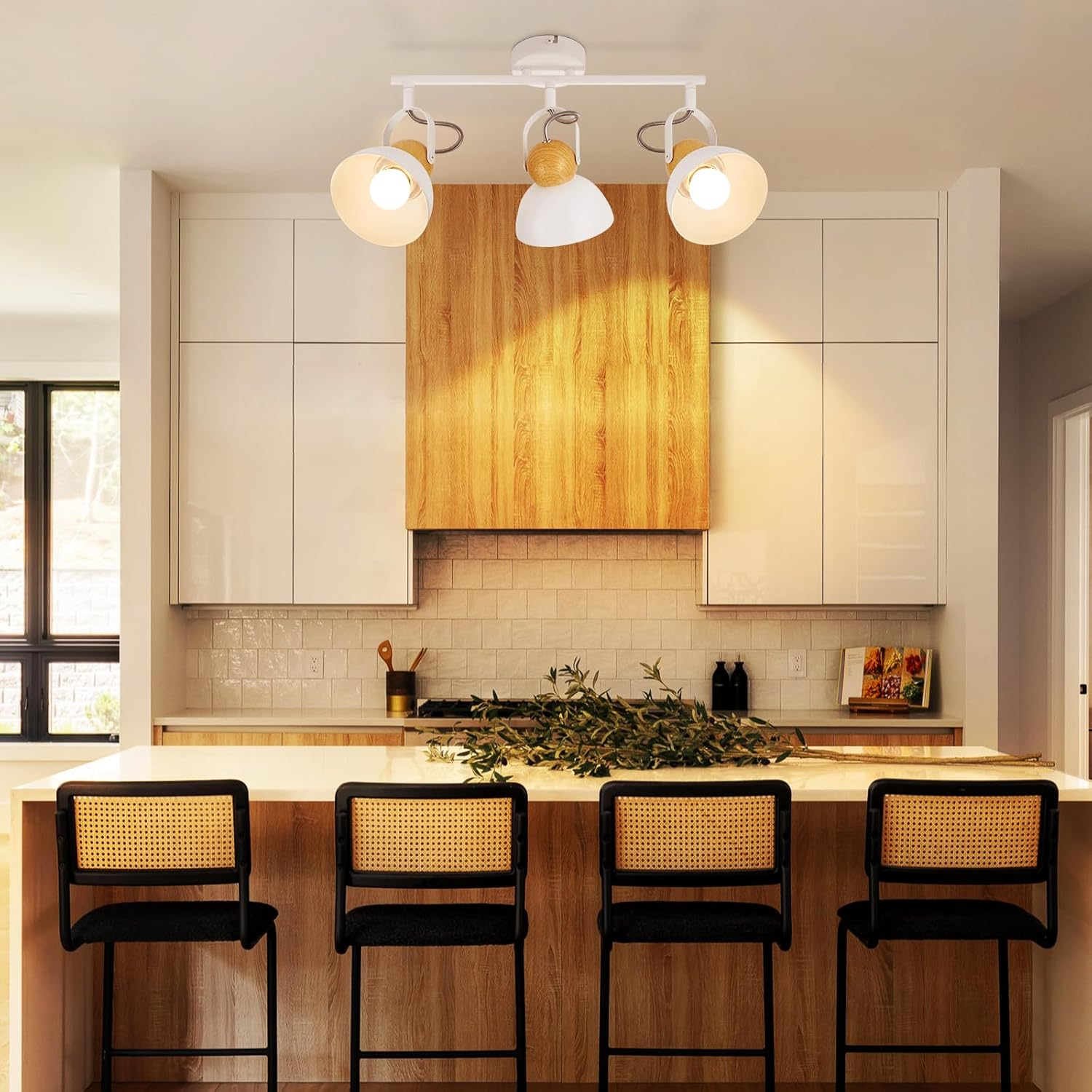 Nowoczesna kuchnia z wyspą, czterema hokerami i lampą szynową.