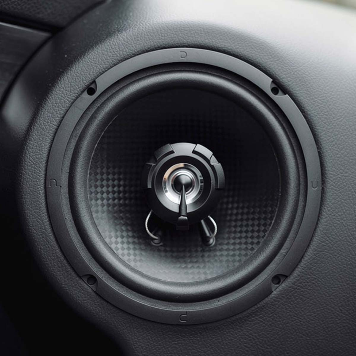 Un haut-parleur de voiture noir avec un tweeter argenté et un cône en fibre de carbone.
