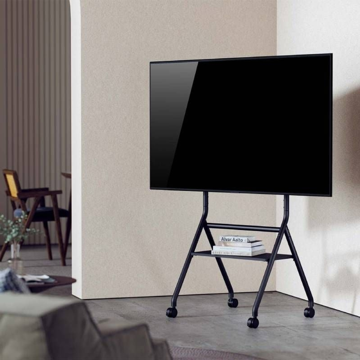 Un televisor negro sobre un soporte rodante negro con libros.