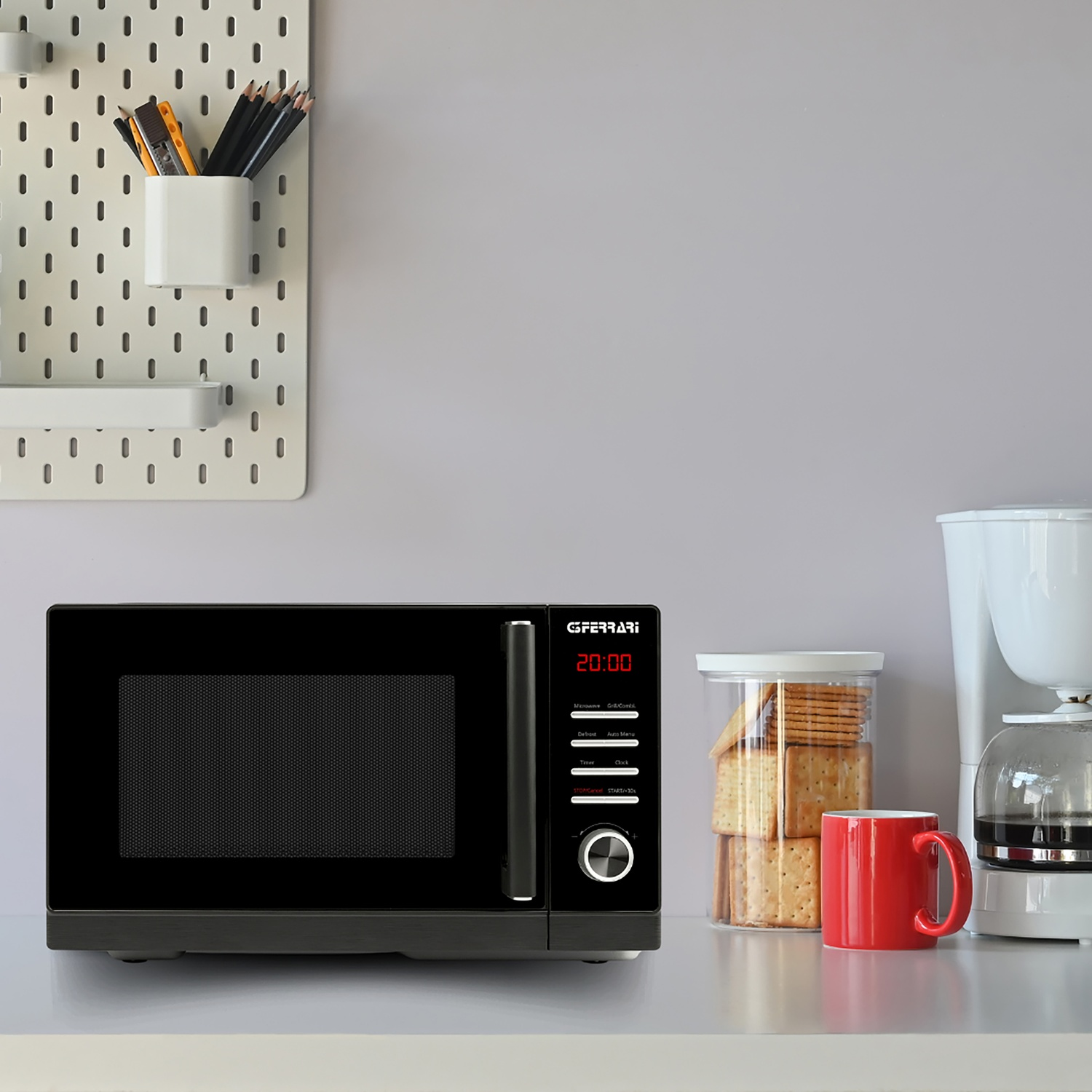 Forno a microonde nero su un bancone con cracker, tazza e caffettiera.