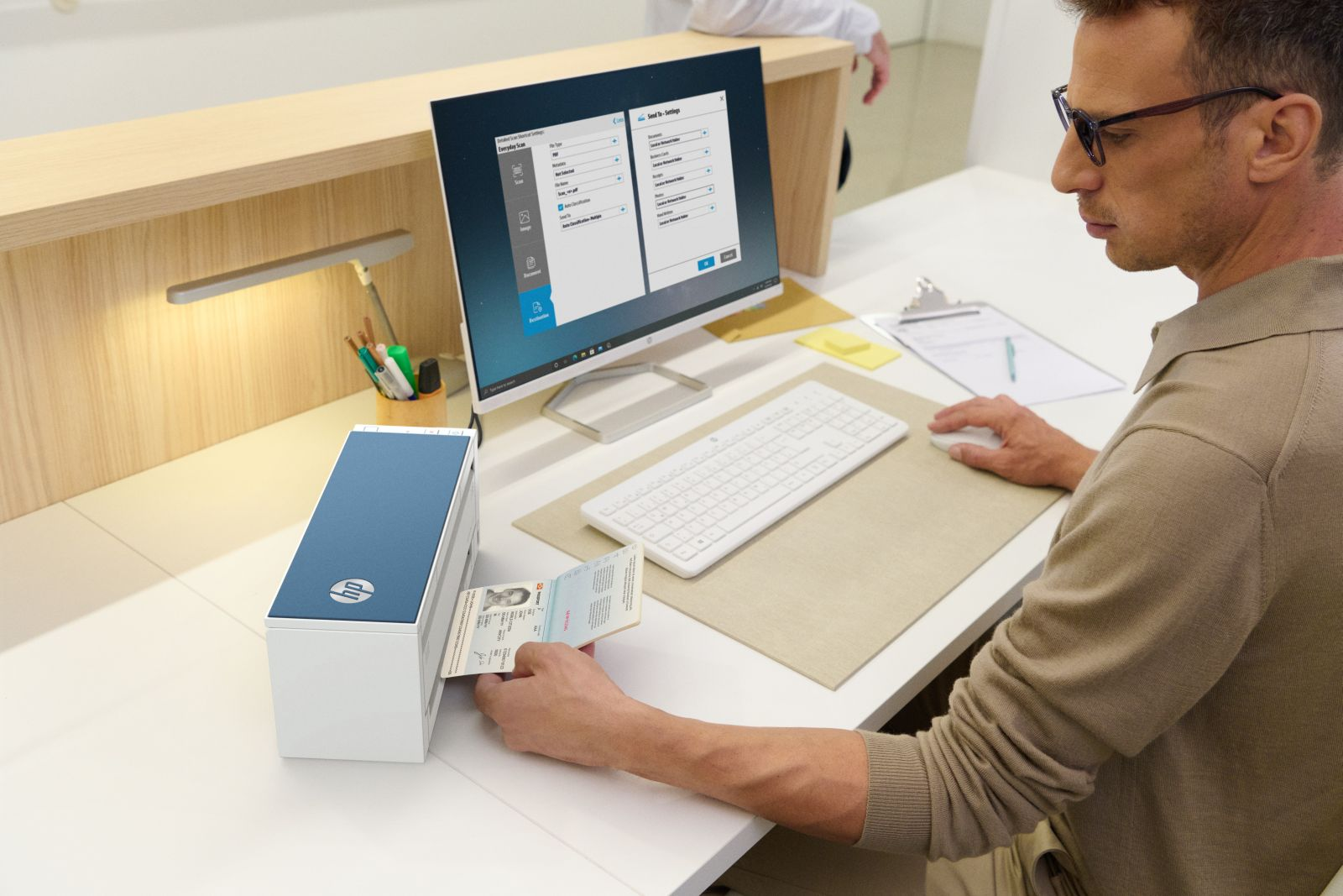 Un uomo scansiona un passaporto con un dispositivo HP mentre guarda lo schermo di un computer.