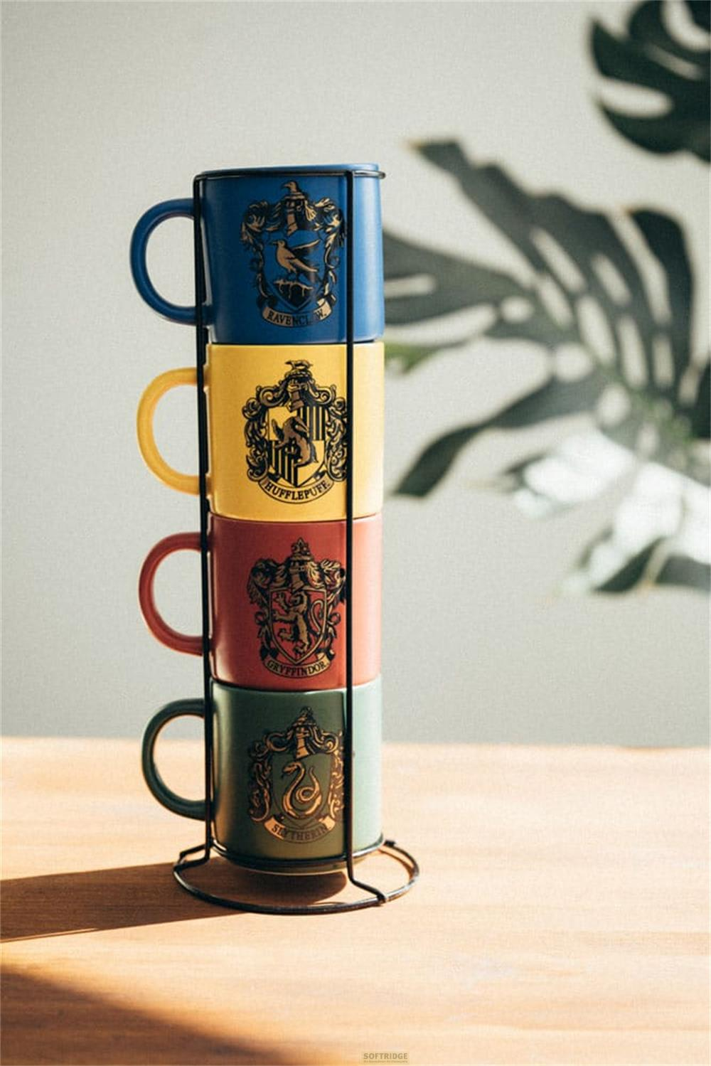 Vier Harry Potter-Tassen in den Farben der Häuser, gestapelt in einem schwarzen Ständer.