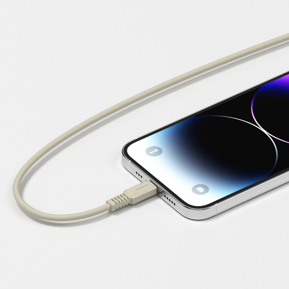 Un câble de chargement beige se connecte à un smartphone argenté sur une surface blanche.