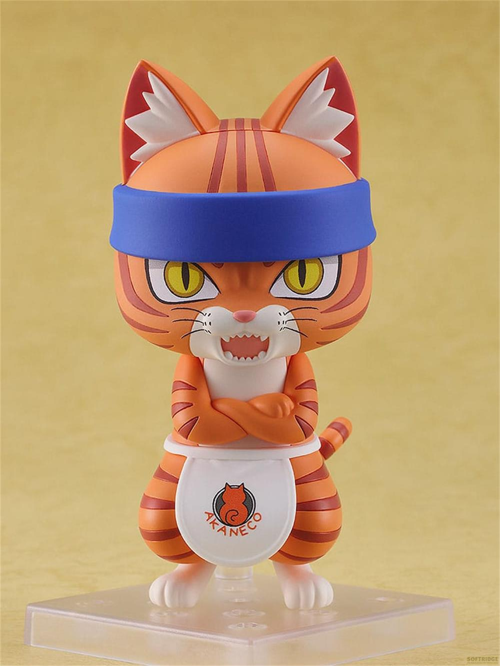 Eine orangefarbene Katze Figur mit blauen Stirnband und weißer Schürze trägt.